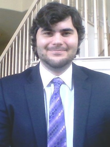 Evan smiling wearing a blue suit and a purple tie